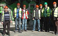 Gruppenbild von sieben M&auml;nnern mit roten Schutzhelmen und gelben Sicherheitswesten