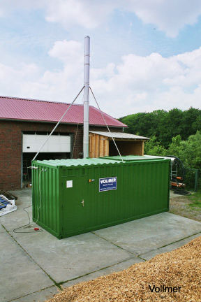 Großer grüner Container mit Edelstahl Schornstein steht auf der Rückseite eines Wohnhausesus