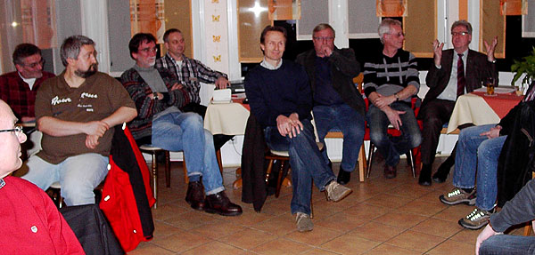 Sechs Männer sitzen den Teilnehmern des Treffens zugewand und geben Erklärungen ab.